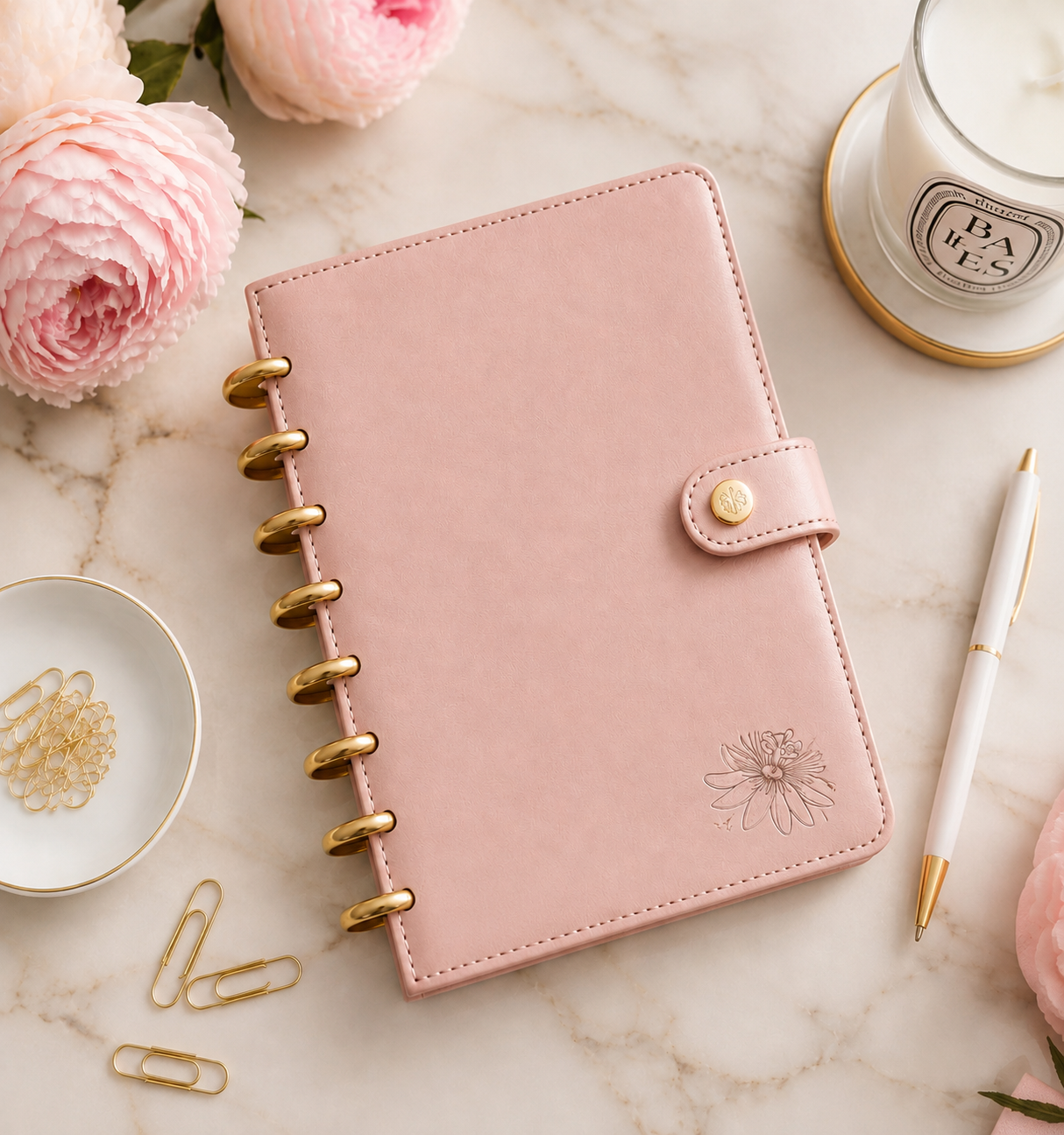 Passiflora Signature Collection planner in rose pearl with gold discs, styled with peonies and a candle